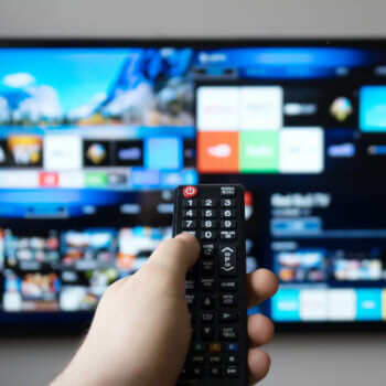 Male hand holding TV remote control. Smart TV.